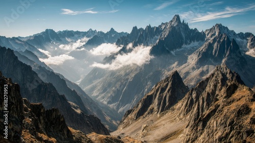 Fototapeta Naklejka Na Ścianę i Meble -  A wide shot of a high-altitude mountain range with sharp peaks and valleys, partially covered in clouds, creating a mystical and dramatic landscape