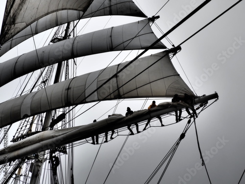 dramatic black and white of sailors furling a sail