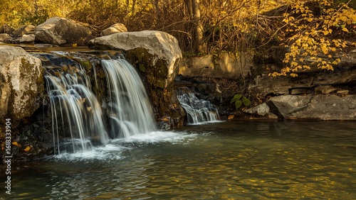 A serene waterfall cascades over rocky terrain, surrounded by autumn foliage in warm golden tones.