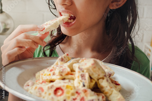Southeast Asian teenage girl eating a plate of full soft and chewy homemade marshmallow nougat cookies for snack