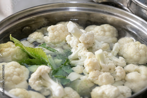 Fresh cauliflower is boiled in a saucepan with water. The vegetable is divided into florets and boiled in a saucepan.