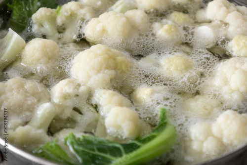 Fresh cauliflower is boiled in a saucepan with water. The vegetable is divided into florets and boiled in a saucepan.