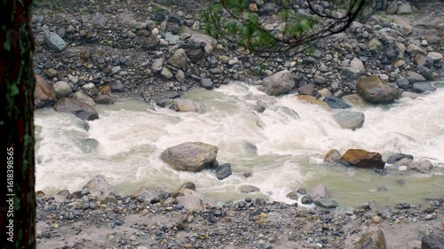 A view of the Mandakini River flowing through the valley between mountains, as seen during the trek to Kedarnath Temple in Kedarnath, Uttarakhand, India.