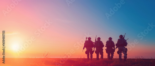 Four soldiers stand in a field at sunset