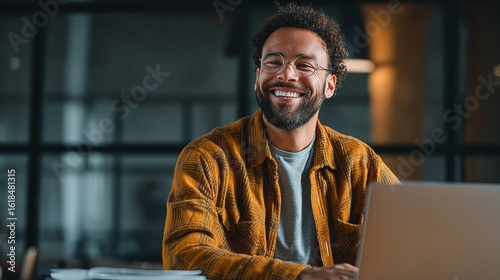 A warm genuine smile from a young professional working late radiating confidence and joy in a modern office with soft