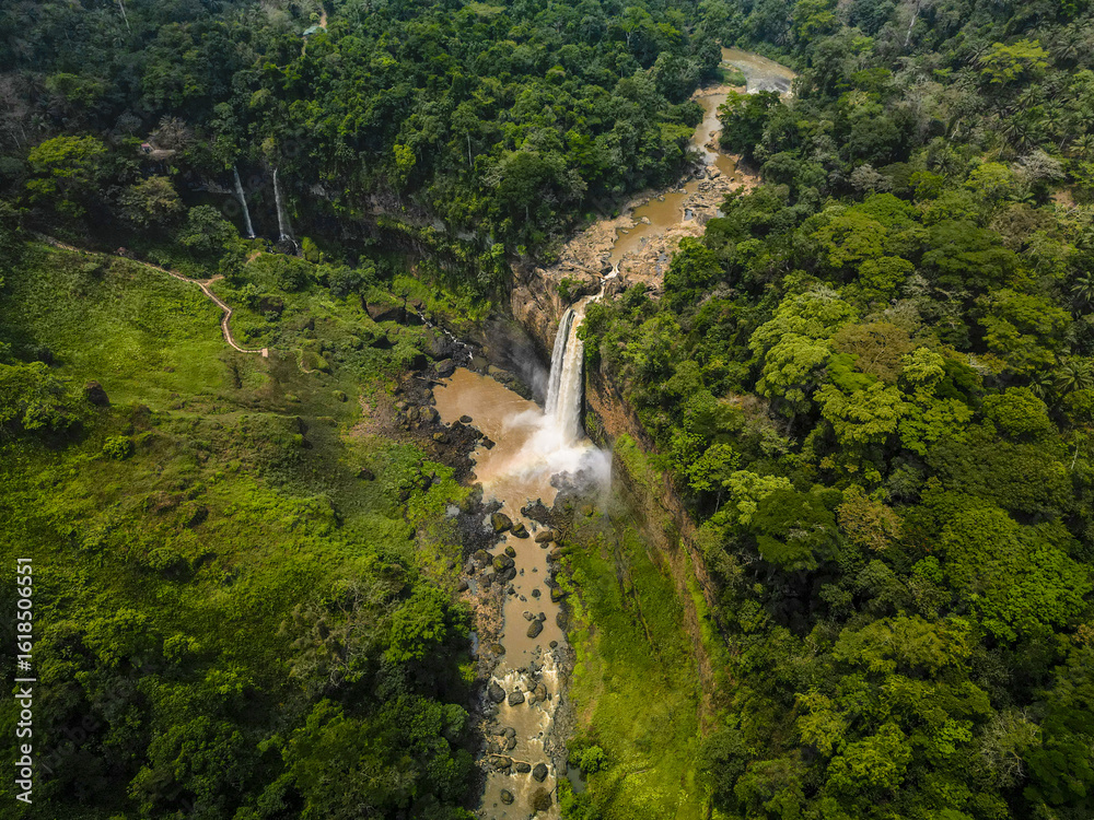 Aerial view of the Ekom-Nkam Waterfalls cascading down rugged cliffs, amidst a symphony of emerald and jade foliage, Nkongsamba, Littoral Region, Cameroon. Aerial view of the Ekom-Nkam Waterfalls cascading down rugged cliffs, amidst a symphony of emerald and jade foliage, Nkongsamba, Littoral Region, Cameroon.