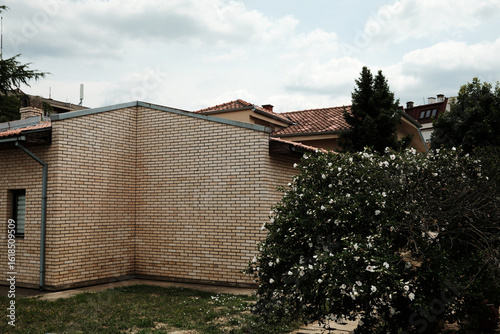 Wallpaper Mural Residential house in Serbia with brick walls and red tile roof, surrounded by flowering bushes and trees. Torontodigital.ca