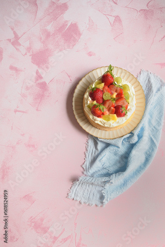 Quadro em tela Vertical image of a strawberry, mango & grape topped cream cake, off-set on a beautiful pink background, with space for copy