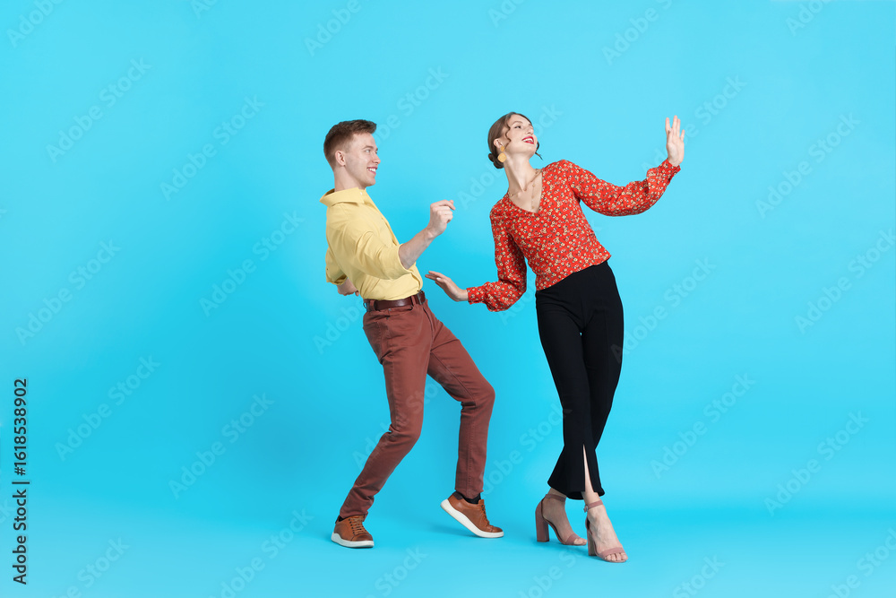 Naklejka premium Happy couple in retro outfits dancing on light blue background