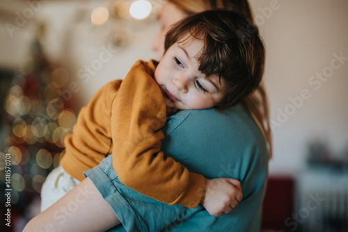 Foto A tender moment of a mother holding her young child close, depicting comfort, care, and love in a warm and peaceful environment