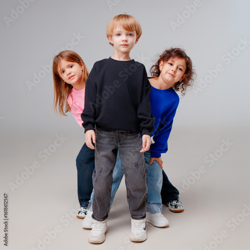 Three kids stand in a playful formation, showcasing their colorful casual outfits. The atmosphere is cheerful and vibrant, ideal for a fashion presentation or campaign.