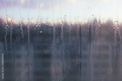 Window with condensation on it and a blurry background. Scene is somewhat melancholic and contemplative