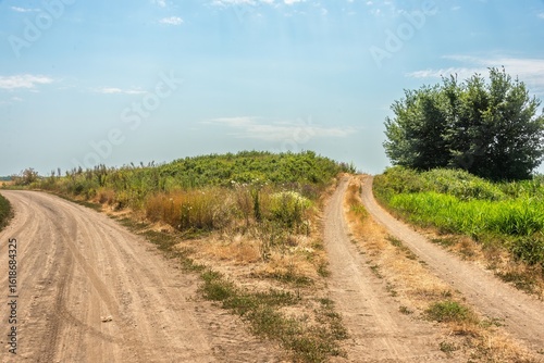 a fork in two country roads that skirt an ancient burial mound on a plain in southern Russia on a hot sunny summer day