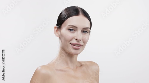 Clear skin beauty model with flawless complexion showcasing skincare routine, wearing minimal makeup, posing confidently against a bright white background, emphasizing healthy skin and self-care	