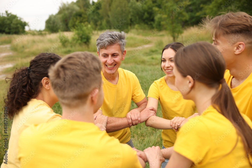 Fototapeta premium Team building. Group of happy people joining hands outdoors