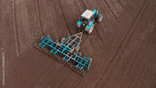 Aerial close up view of a tractor with a grain seeder works in the field