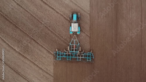 Shot from above of the tractor with a grain seeder is working in the field