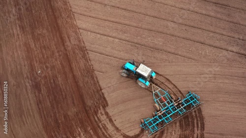 Top down view of tractor with a grain seeder is working in the field