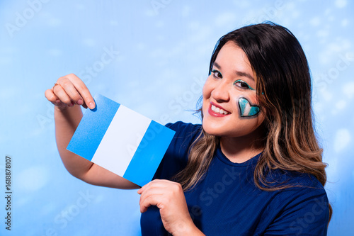 Smiling Woman with Artistic Makeup Holding the Flag of Guatemala on Blue Background