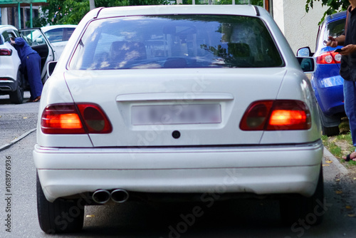 Car parked on a street near a building during the daytime with people nearby engaged in different activities