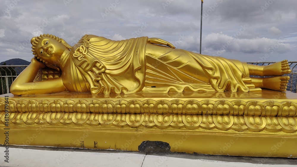 Fototapeta premium A reclining Buddha gold plated with Cloudy sky.