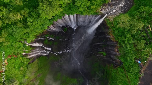 Aerial drone video of  Tumpak Sewu Waterfall in the tropical forest of East Java, Indonesia, drone flying above the waterfall. 

