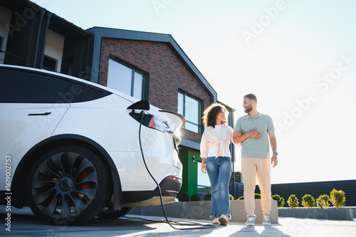 Fotografía Couple walking near their electric car charging at home
