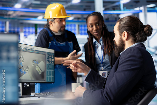 Photovoltaics factory manager working with solar engineering team, improving systems reliability. Alternative energy solar panel manufacturing plant expert providing feedback to workers