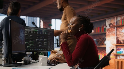 Obraz na plátně Programmer coding AI algorithm in startup, eating food at desk while refining machine learning models