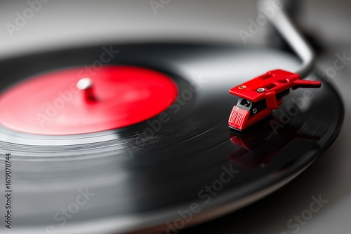 Close up of vinyl record spinning on turntable with red label and stylus needle in motion
