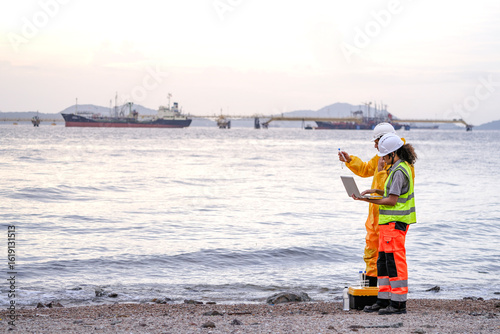 Two field scientists in PPE gear analyzing seawater samples using test tubes and a laptop. Environmental monitoring and pollution control on the coastline are depicted.