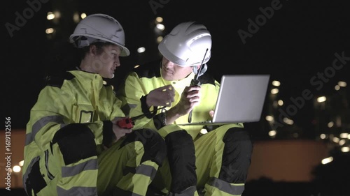 Engineers Reviewing Plans at Industrial Site at Night, Team of Industrial Workers with Laptop, Engineers Collaborating at Manufacturing Plant