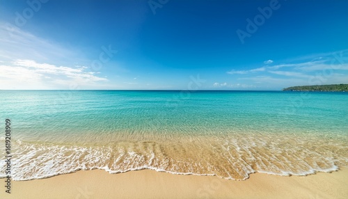 calm and clear turquoise water gently laps against a golden sandy beach during a bright sunny day creating a serene coastal atmosphere