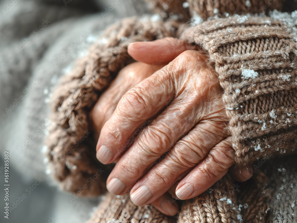 Fototapeta premium Close-up of senior woman's wrinkled hands, covered by warm woolen sleeves, seeking warmth and comfort during cold winter day, highlighting themes of aging, loneliness, and vulnerability