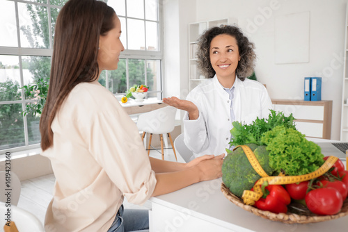 Mature female nutritionist working with client at table in office