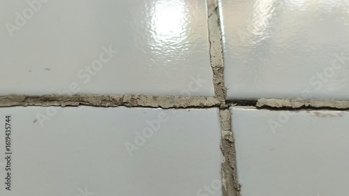 The floor grout in the room is damaged and dirty.
