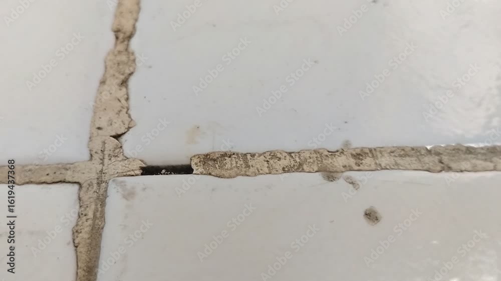 The floor grout in the room is damaged and dirty. The floor grout in the room is damaged and dirty.