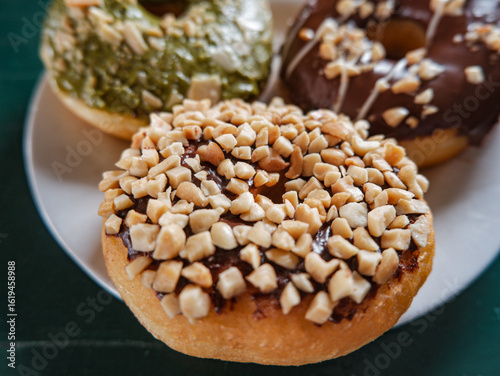 close up picture of donuts with various flavour. matcha, peanut and chocolate donuts in white plate