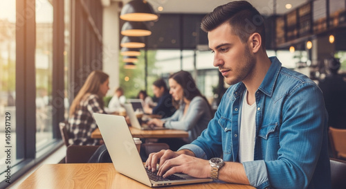 Young man working remotely on laptop in modern cafe with relaxed atmosphere.