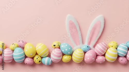 Pastel easter eggs line a pink surface with cute bunny ears poking above springtime festive celebration