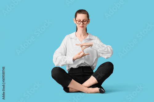 Young businesswoman meditating on blue background