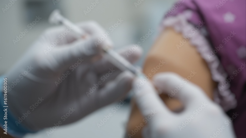 Fototapeta premium Blurry image of a medical worker wearing gloves while administering a vaccination. Concepts of vaccination, safety, medical care, and the hospital environment with a shallow depth of field.