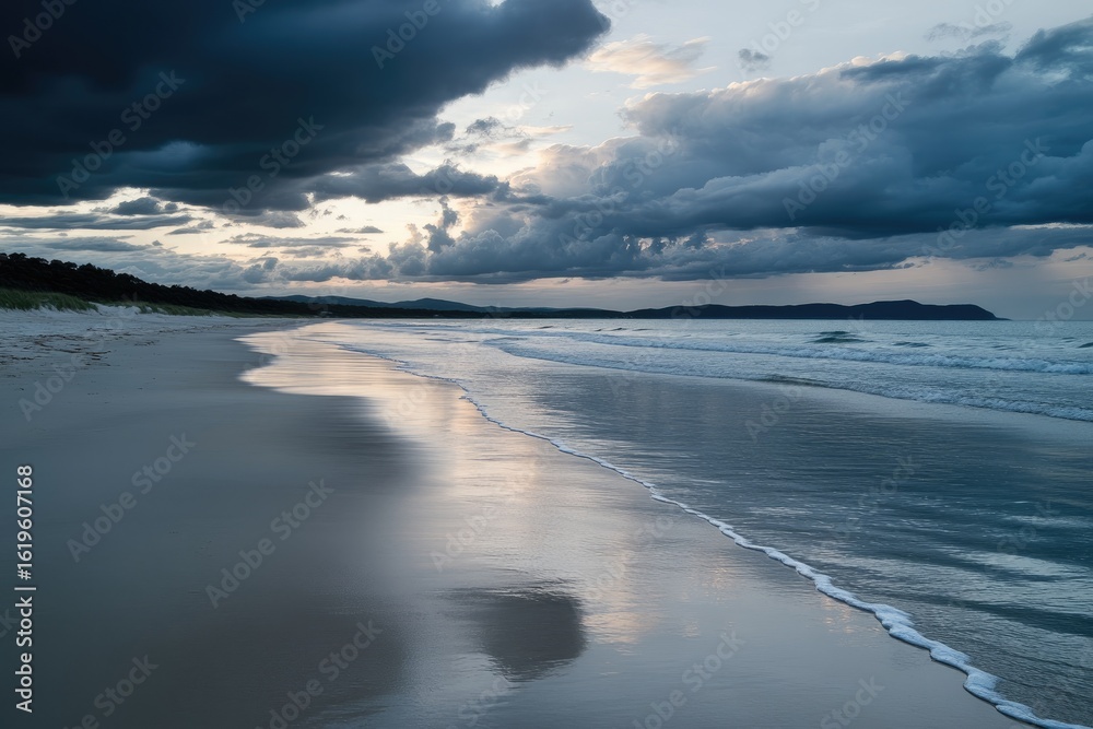 Fototapeta premium Calm beach at dusk, with dramatic clouds