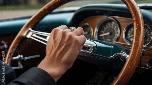A man’s hand gripping a steering wheel of a classic car 