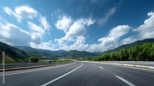Asphalt Highway with Lush Green Mountains Under Fluffy Clouds