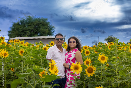 Romantic Couple Posing in Vibrant Sunflower Field Under Dramatic Sky

