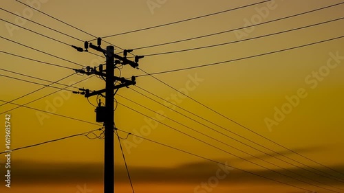 Silhouette of utility pole and wires at sunset