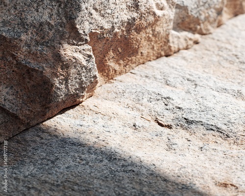 Jagged rock surface layered with speckled granite under midday direct sun.