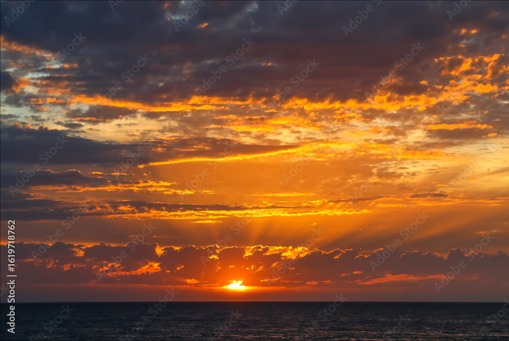 Fototapeta premium Dramatic ocean sunset with golden rays and glowing clouds, Australia