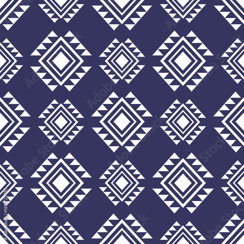 Seamless geometric pattern featuring white diamonds and triangles on a deep indigo background Repetitive traditional